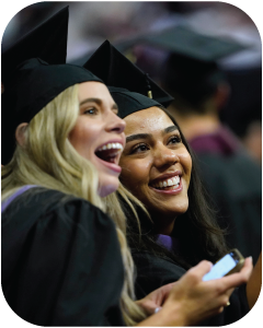 Two business students smiling at graduation.