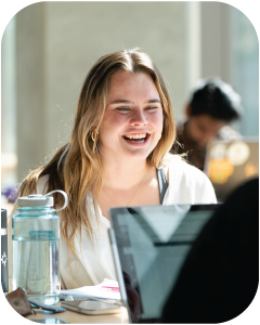A marketing student laughing at a table while studying.