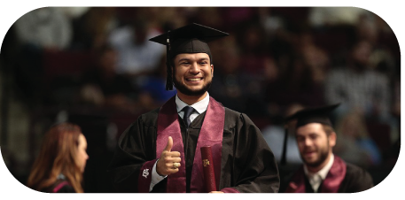 A student smiling at graduation on stage.