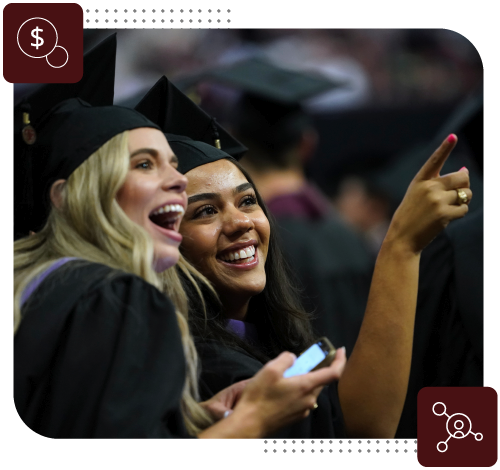 Two students smiling and pointing at graduation.