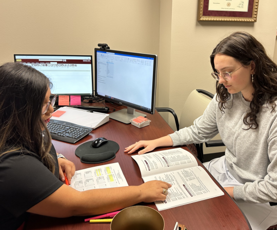 A female advisor helping a student look through a course booklet.