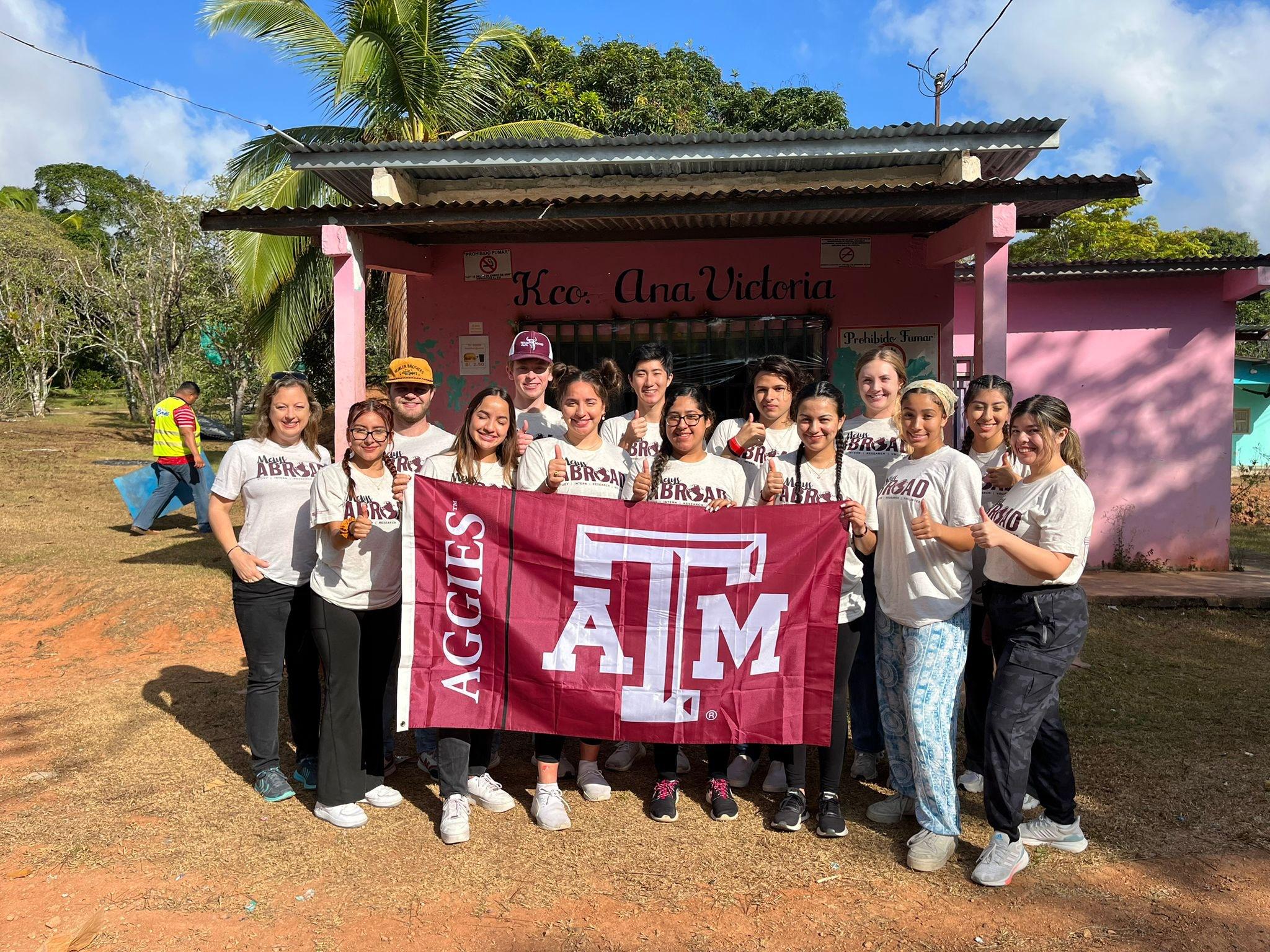 Study abroad students pose with Texas A&M banner.