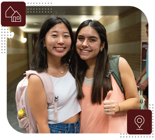 Two female students smiling in the Wehner hallway.