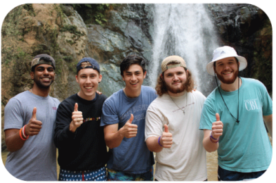 Five study abroad students smiling in front of waterfall.