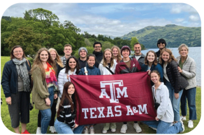 Students and faculty pose with Texas A&M banner on study abroad.