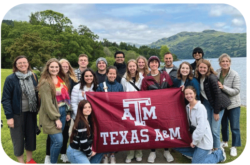 Students and faculty pose with Texas A&M banner on study abroad trip.