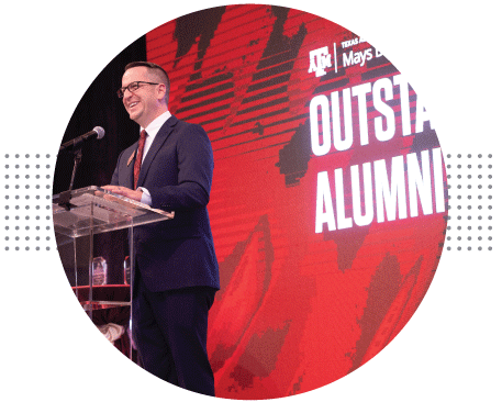 Speaker talking on stage at Outstanding Alumni event.