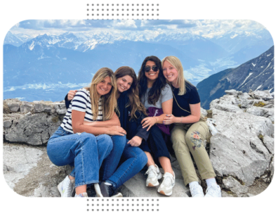 Four students smile together in front of mountains. 