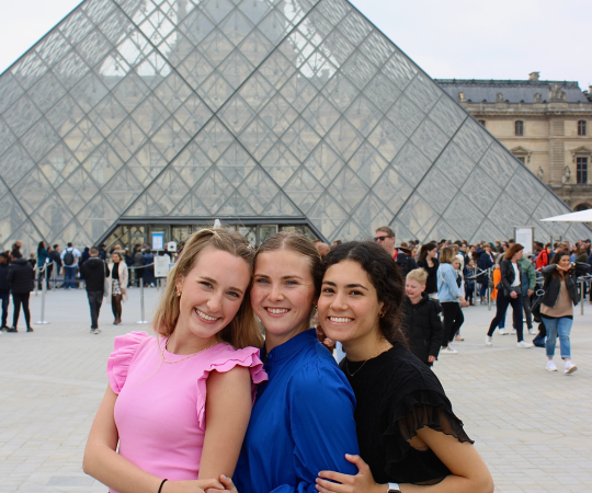 Three students pose in front of the Louvre Museum in Parise, France.