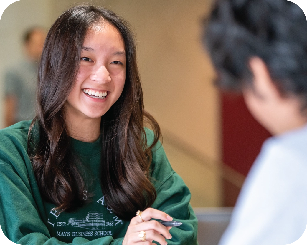 A female student holding her laptop and smiling on campus.