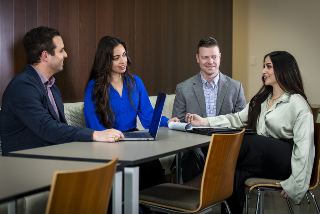 Four students in business dress talking around a table