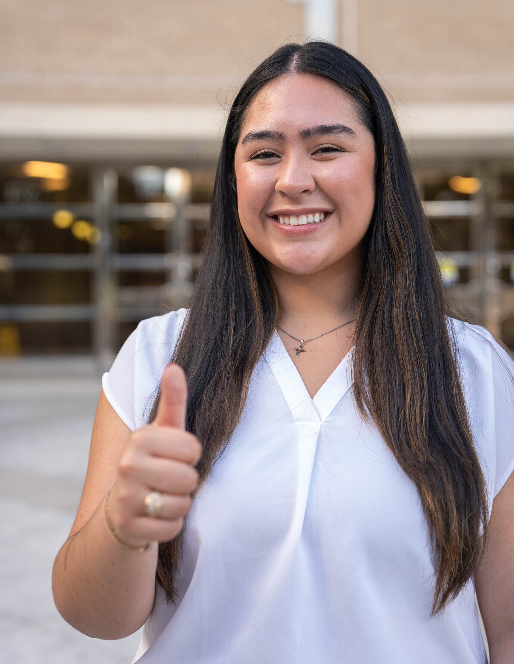 Student standing outside smiling and giving a thumbs up