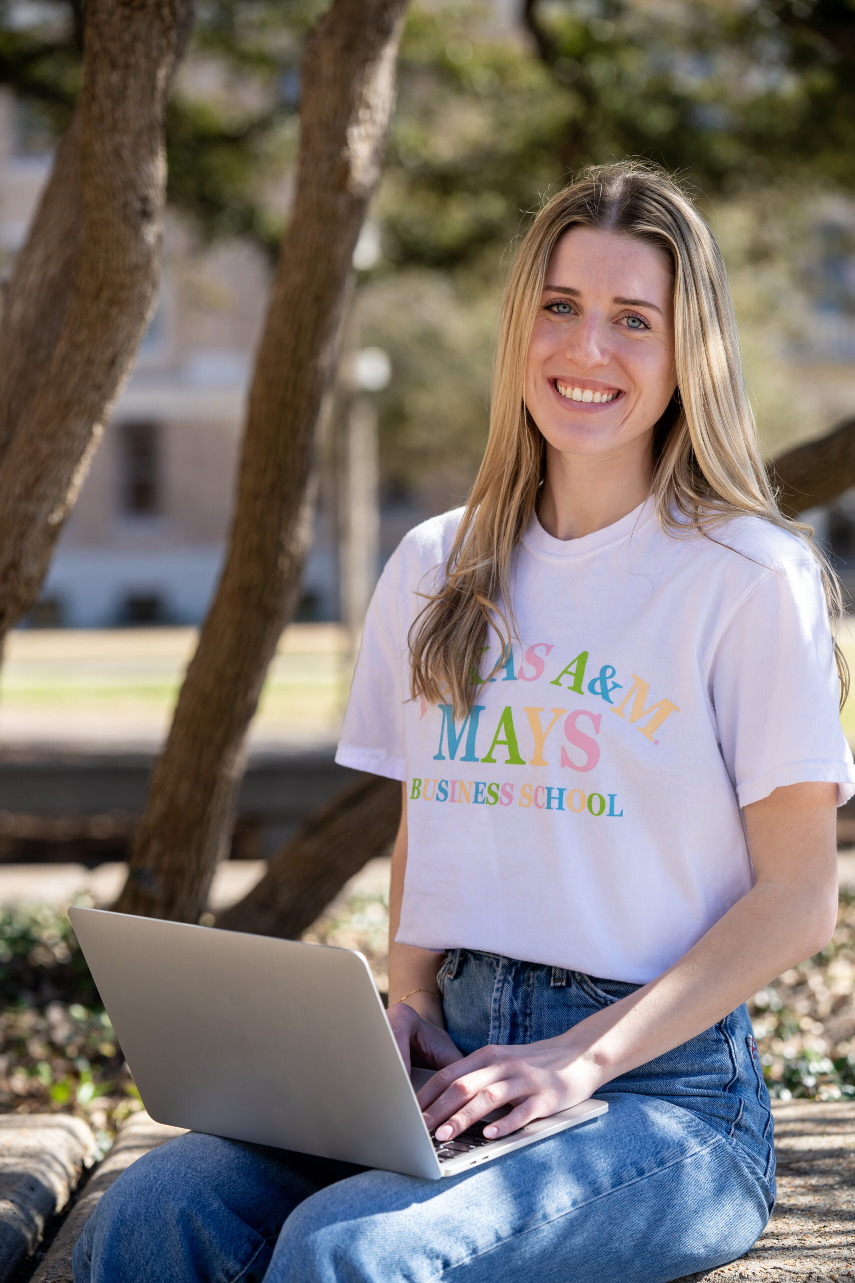 Student sitting in the shade outside with her laptop