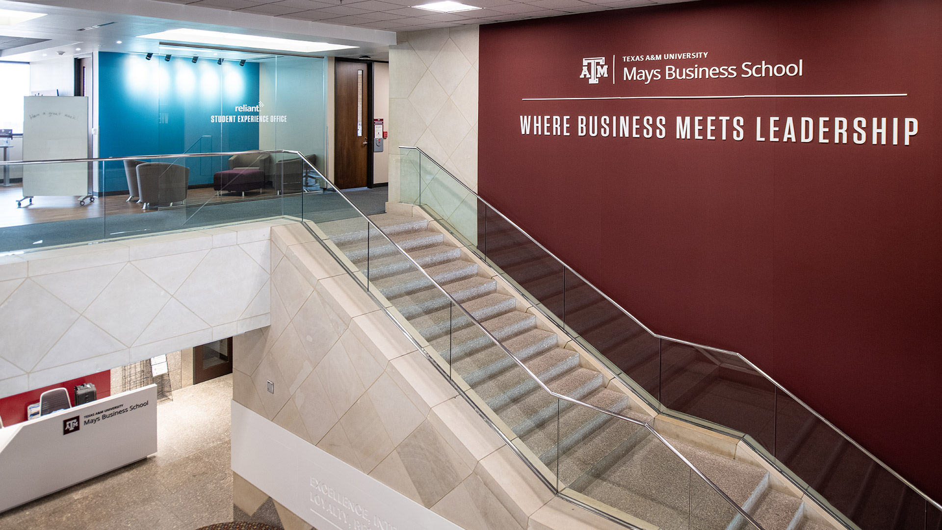 A grand staircase in the Wehner building, the maroon wall says "Where Business Meets Leadership"